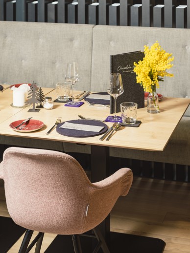 Restaurant im Kleinwalsertal mit gelben Blumen und Gedeck auf dem Holztisch für vegane Gerichte im Oswalda Hus.