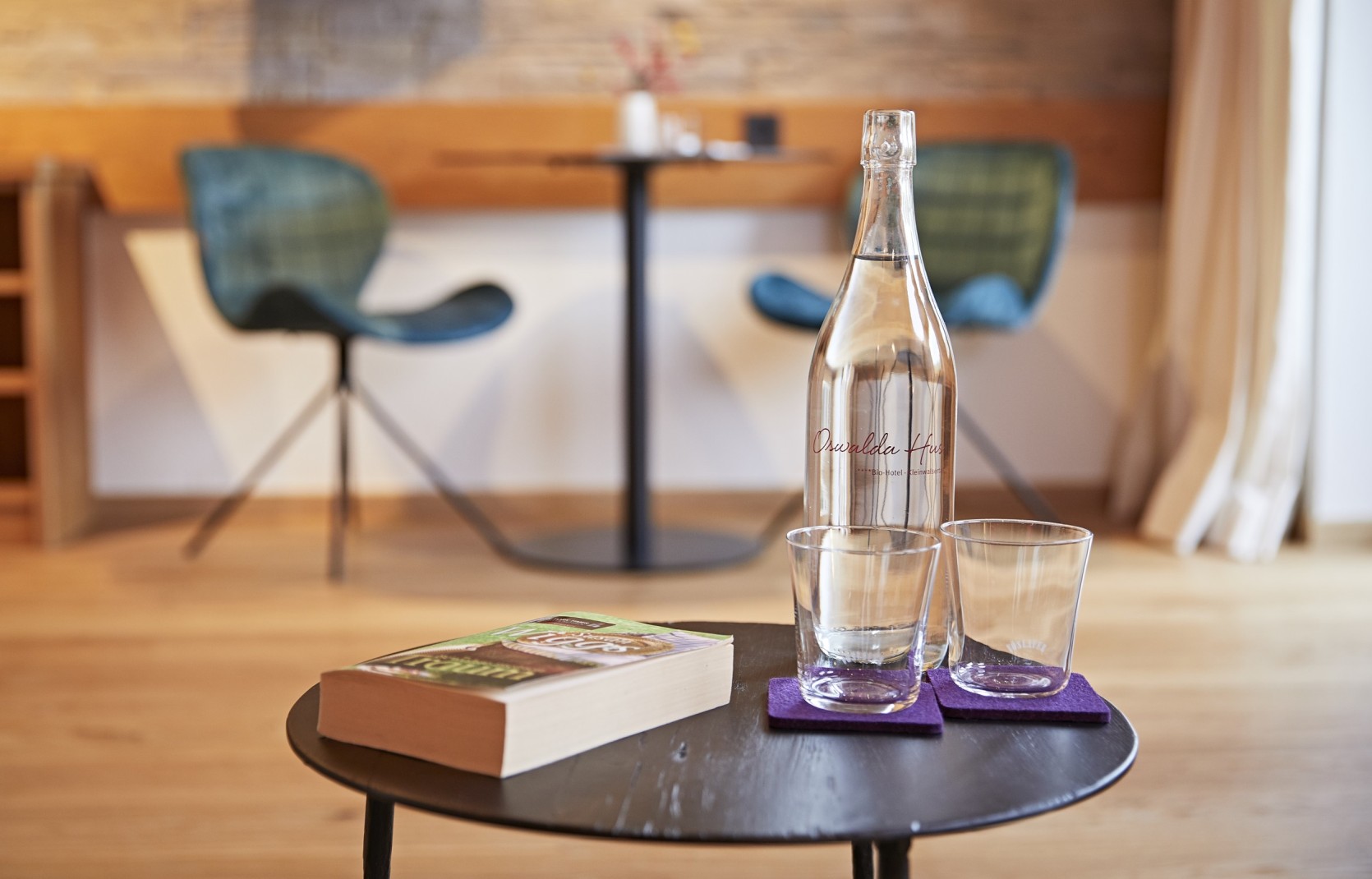 Beistelltisch mit Buch und Wasser in einer Suite im Oswalda Hus Hotel Kleinwalsertal.