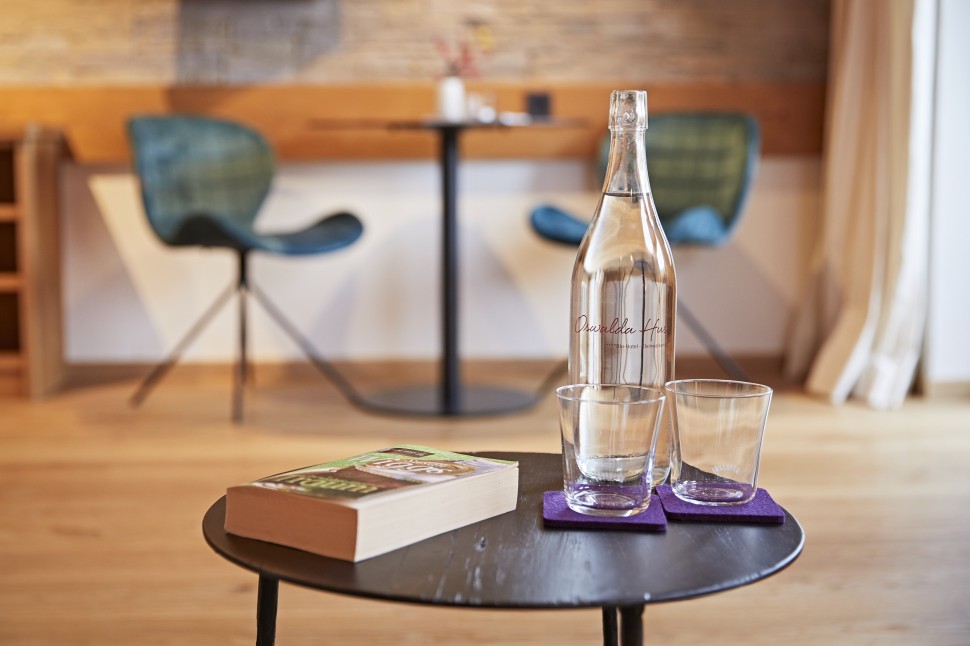 Beistelltisch mit Buch und Wasser in einer Suite im Oswalda Hus Hotel Kleinwalsertal.