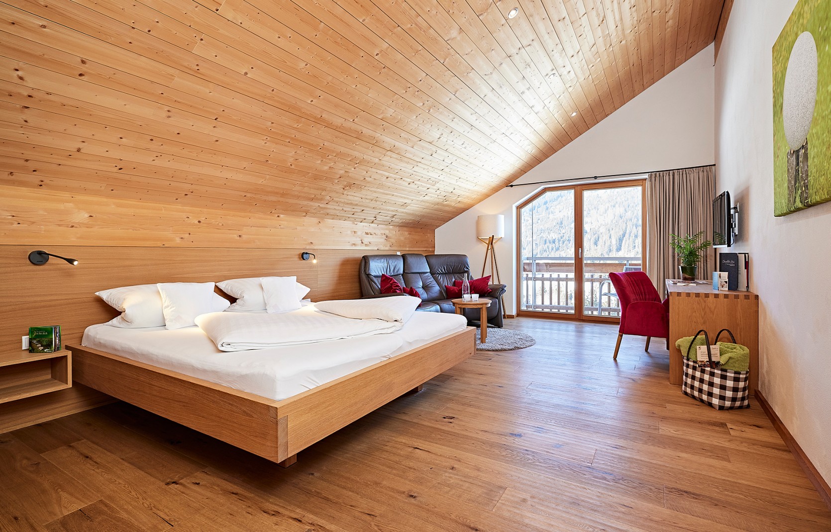Hotelzimmer im Dachgeschoss mit Holzwänden, Balkon und Sofa im Oswalda Hus Hotel Kleinwalsertal.