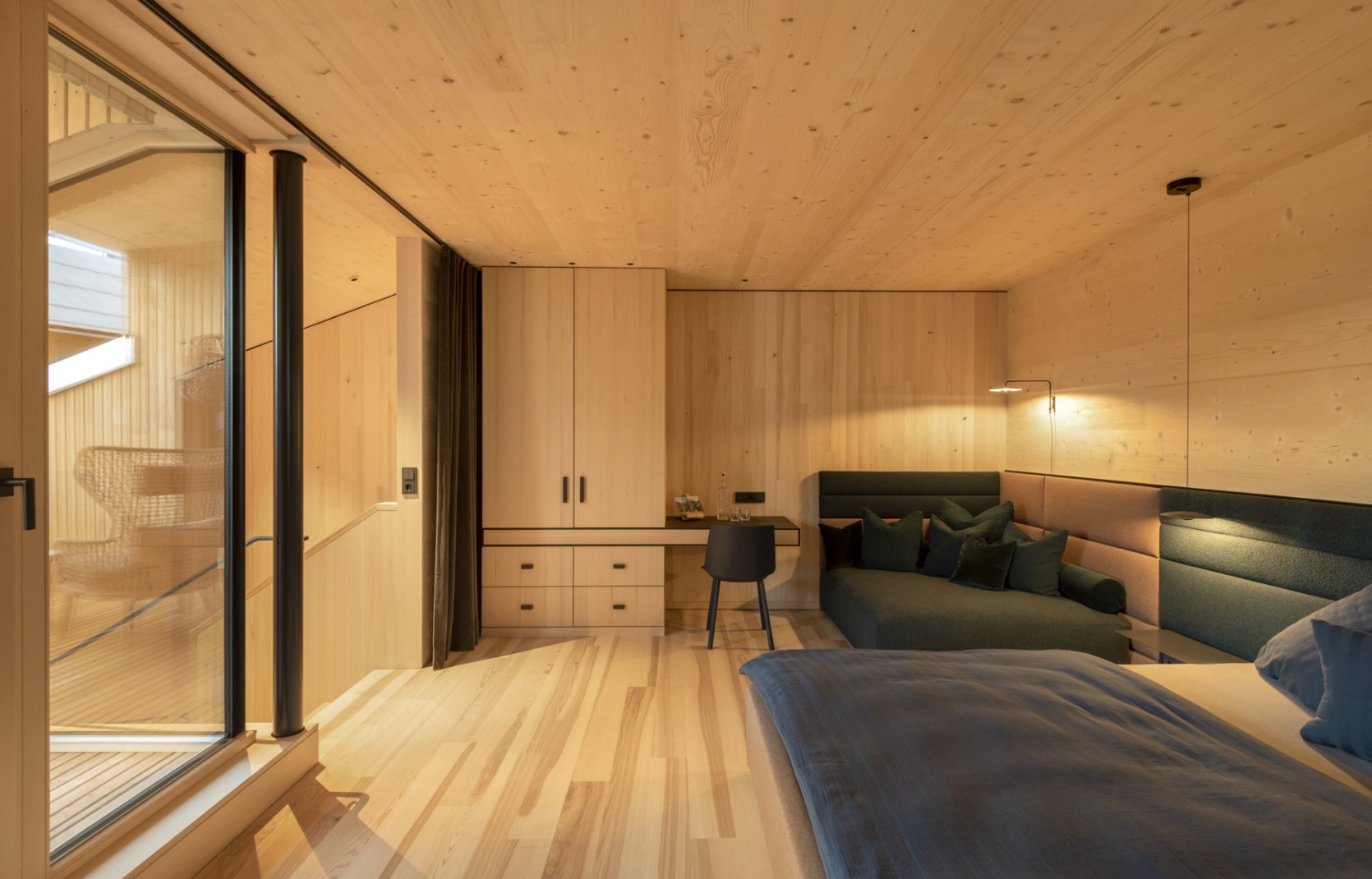 Geräumiges Hotelzimmer mit Balkon, Sitzecke, Schreibtisch und Holzwänden im 4 Sterne Hotel Oswalda Hus Kleinwalsertal.