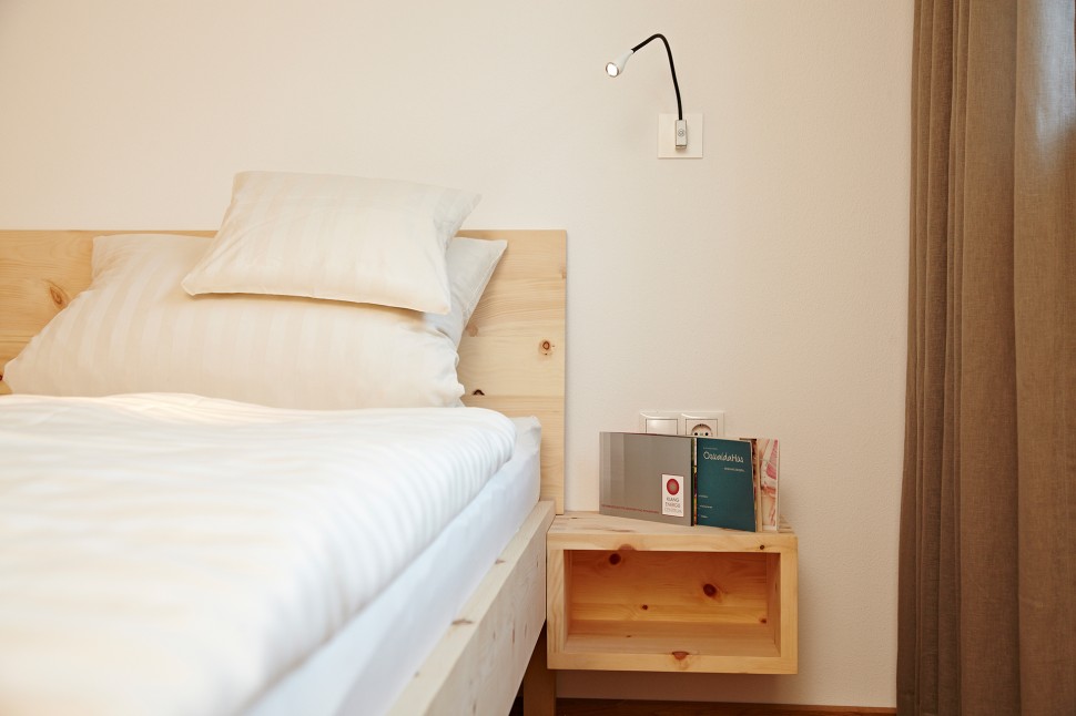 Geräumiges Hotelzimmer mit Holzbett im 4-Sterne-Hotel Oswalda Hus im Kleinwalsertal.