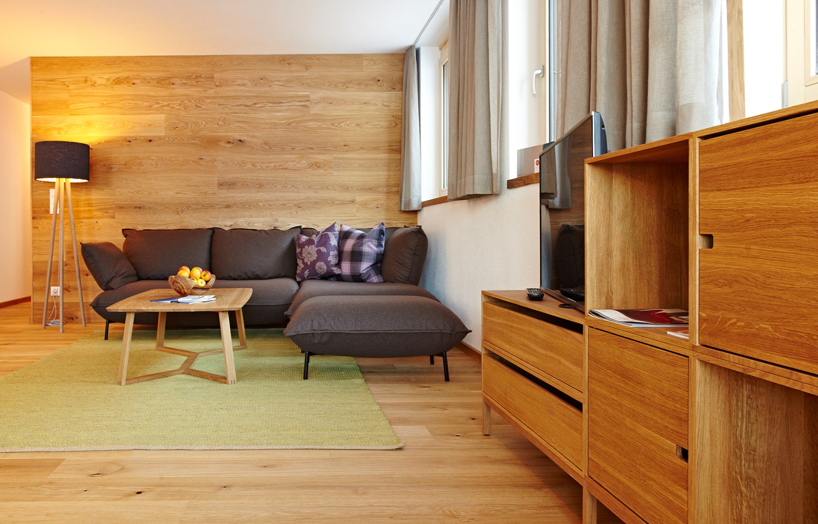 Ferienwohnung mit Sofa, Holzwand und grünem Teppich im Oswalda Hus Kleinwalsertal.