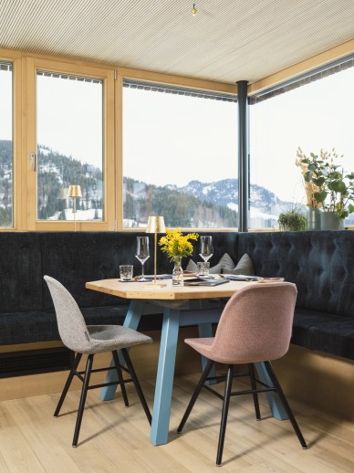 Oswalda Hus Restaurant im Kleinwalsertal mit bunten Möbeln, Bergblick und gedecktem Tisch.