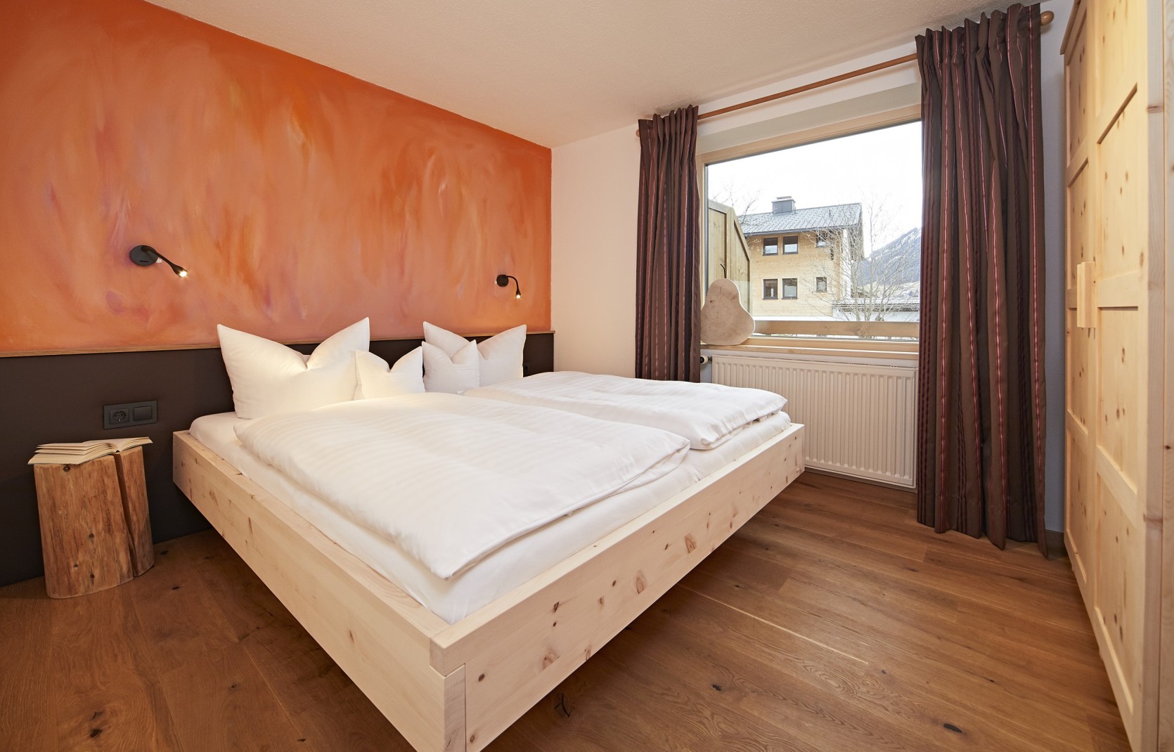 Hotelzimmer mit roter Wand und Holzmöbeln im Hotel Oswalda Hus Kleinwalsertal.