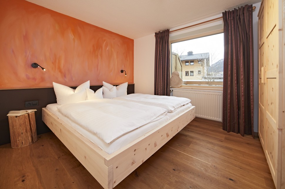 Hotelzimmer mit roter Wand und Holzmöbeln im Hotel Oswalda Hus Kleinwalsertal.