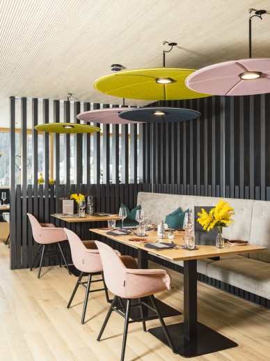 Restaurant im Kleinwalsertal mit bunten Möbeln und Lampen, Holzboden und gedecktem Tisch im Oswalda Hus.