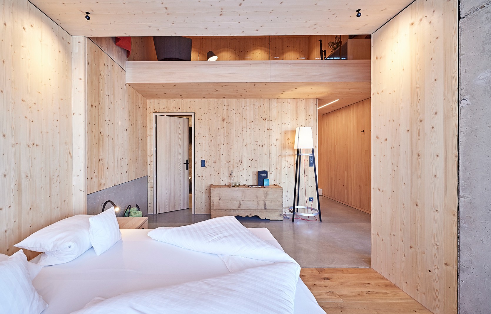 Schlichtes Hotelzimmer mit Holzwänden, Sichtbeton und roten Vorhängen im 4 Sterne Hotel Oswalda Hus im Kleinwalsertal.