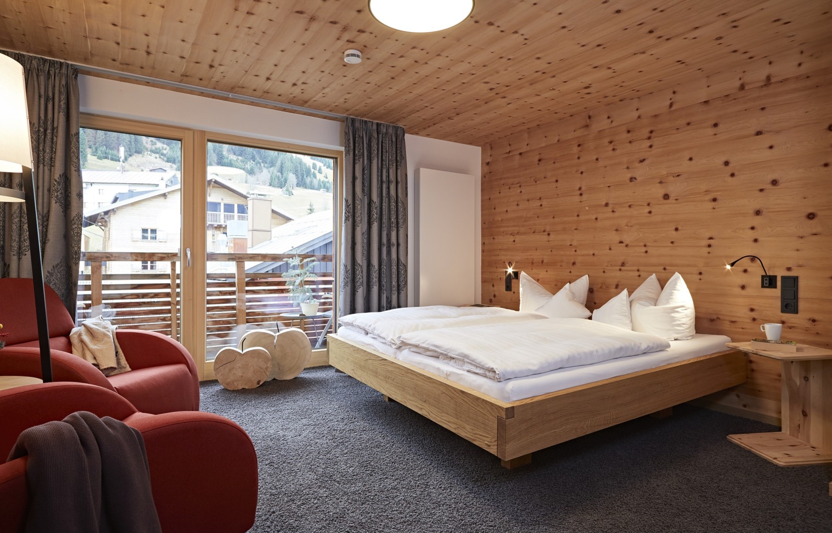 Geräumiges Hotelzimmer mit Balkon, Sitzecke, Schreibtisch und Holzwänden im 4 Sterne Hotel Oswalda Hus Kleinwalsertal.