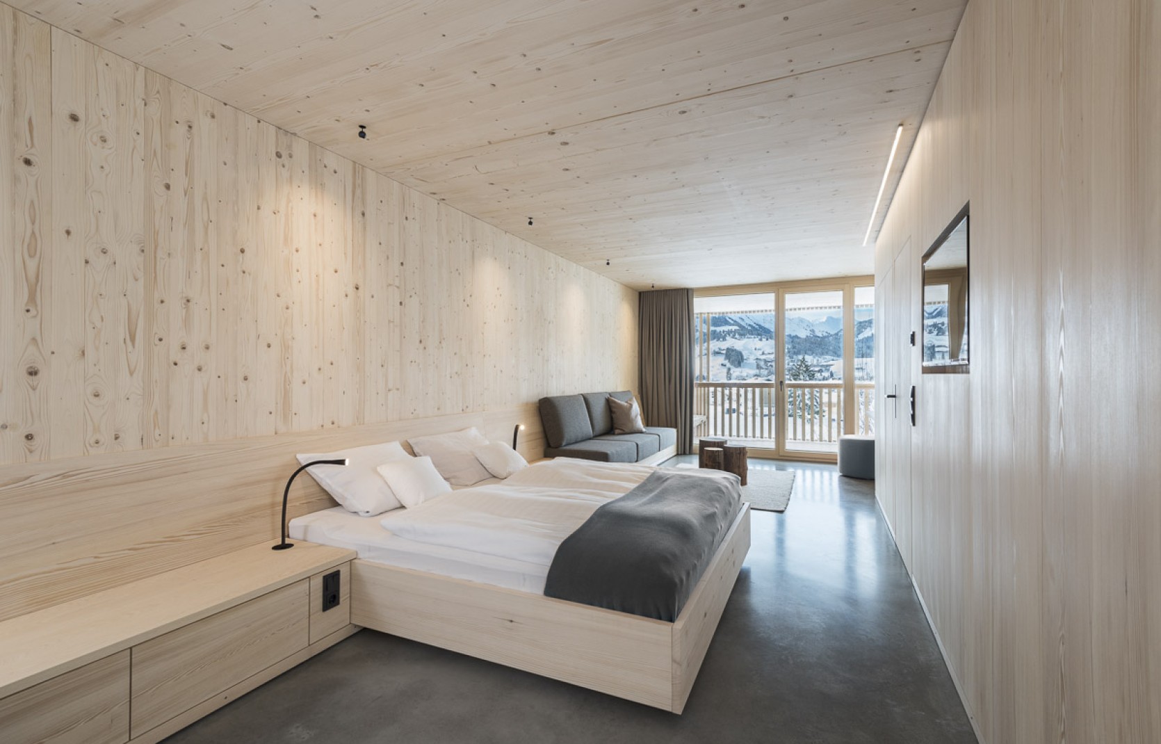 Schlichtes Hotelzimmer mit Holzwänden, Sichtbeton und grauen Vorhängen im 4 Sterne Hotel Oswalda Hus im Kleinwalsertal.