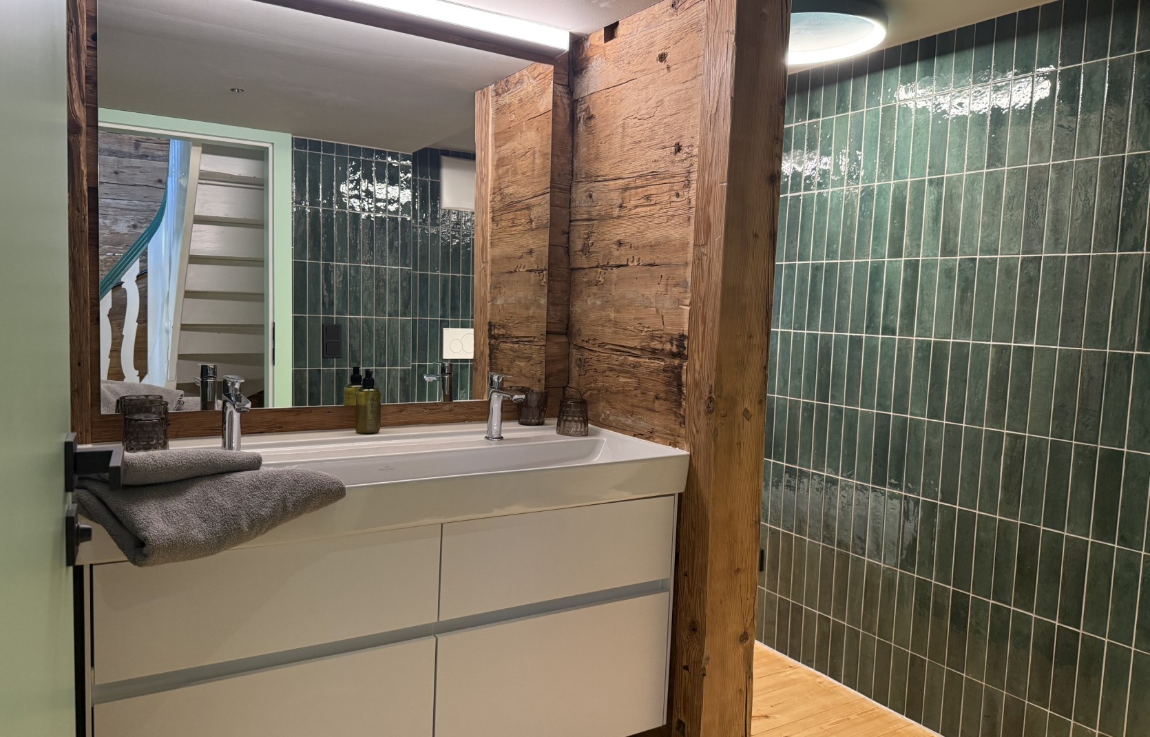 Badezimmer mit grünen Fließen und Altholz im Oswalda Hus Ferienhaus Kleinwalsertal.