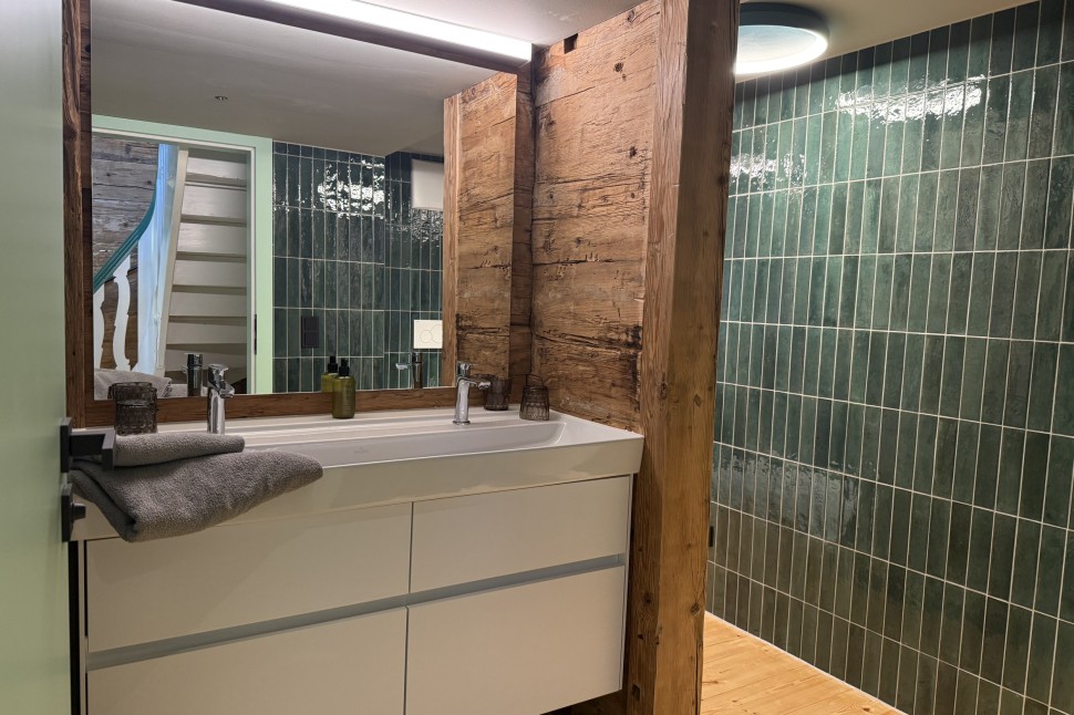 Badezimmer mit grünen Fließen und Altholz im Oswalda Hus Ferienhaus Kleinwalsertal.