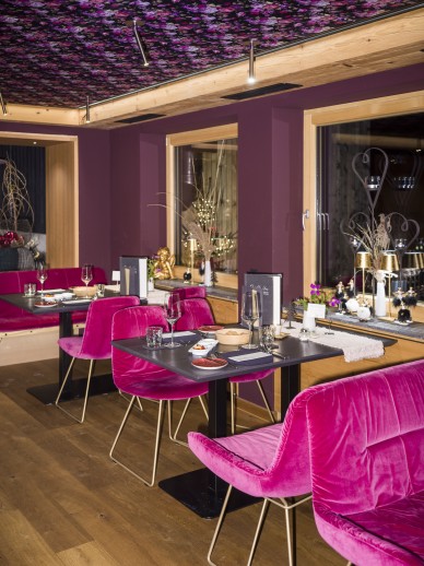Gedeckte Tische mit pinken Stühlen im Oswalda Hus Restaurant im Kleinwalsertal.