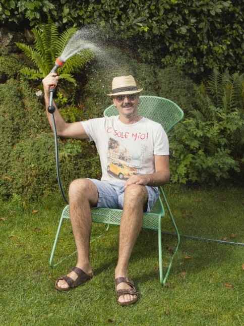 Abkühlung im Garten mit Wasserschlauch als Symbol für das Wellnesshotel im Kleinwalsertal Oswalda Hus.