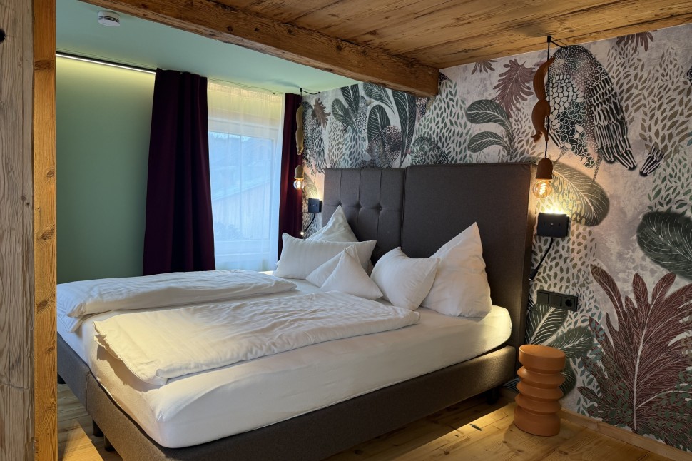 Schlafzimmer mit gemusterter Tapete und Polsterbett im Oswalda Hus Ferienhaus Kleinwalsertal.