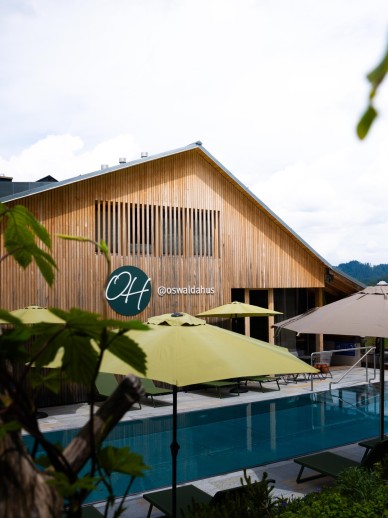 Außenpool mit Sonnenschirmen und Liegen im Wellnesshotel Oswalda Hus Kleinwalsertal.